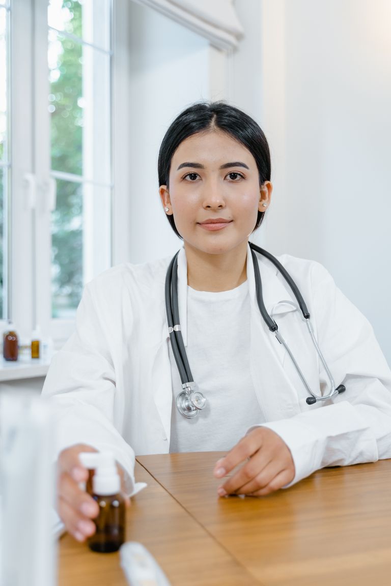 Professional young female doctor sitting indoors in a hospital with a smile.