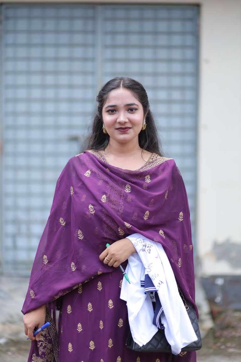 Young woman in purple traditional dress holding documents outdoors.